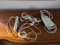 Three white power accessories: two power strips and an extension cord laid on wooden surface