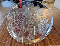 Front view of clear pressed glass plate showing fruit embossing