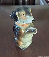 Front view of dachshund teapot showing raised paw spout and facial detail