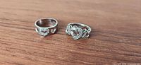 Both sterling silver rings side by side on wood surface