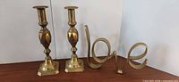 Full lot: two brass candlesticks, brass love sculpture
