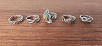 All five sterling silver rings lined up showing variety of designs