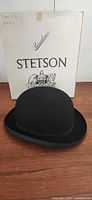 Front view of black bowler hat with Stetson box backdrop