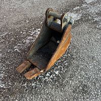Side perspective of rusted 7.5in excavator bucket on pavement