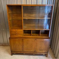 Front view of wood and glass hutch showing shelving and lower cabinet
