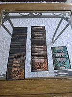 Stacks of cards showing brown Jyhad backs, black Vampire backs and green promo backs on glass table