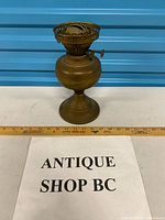Full view of brass oil lamp base next to ruler