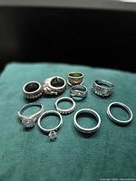 Group of ten rings on green fabric showing variety of styles and finishes