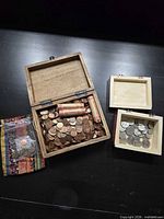 Open boxes showing quantity of loose pennies, coin rolls, smaller box with silver-toned coins, zip bag and textile pouch