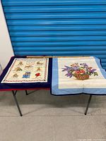 Overview of both cross-stitch pieces on table