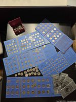Overview of blue Whitman folders with coins, loose coin box, sealed dollar coins on tabletop