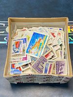 Small open box filled with loose cancelled Canadian stamps