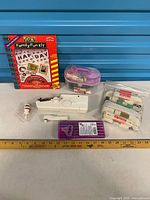 Entire lot overview showing CD-ROM box, handheld sewing machine, sewing kits, elastic packs, thread spool
