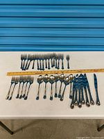 Entire set laid out showing forks, spoons, knives with ruler for scale