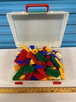 Open storage case filled with colorful bristle blocks, ruler for scale
