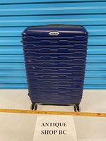 Full front view of blue Samsonite hard-shell suitcase on wheels
