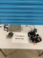 Two PlayStation consoles, controllers, cables on table