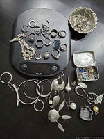 Full lot on table with digital scale, rings on scale, earrings, bowl, tin visible