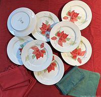 Overhead view showing eight dinner plates, red tablecloth beneath, red and green napkins at side