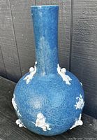 Front view of blue glazed porcelain bottle vase showing white relief figures and pomegranates