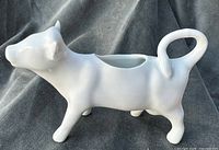 Left side view of white ceramic cow creamer pitcher