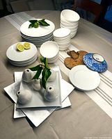 Assortment of stacked white plates, bowls, square platter, and pear-shaped vases