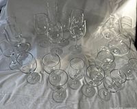 Full group of 18 clear glass stemware pieces displayed on white cloth