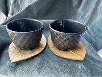 front view of two cups each on a leaf-shaped coaster