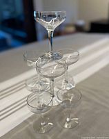 Stack of eight clear stemmed coupe glasses showing bowl and stem style