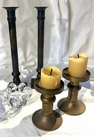 Group shot of two brass short candlesticks and two tall black metal candlesticks