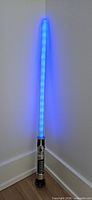 Lightsaber lit and standing in corner showing full blue blade