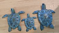 Front view of all three metal sea turtles showing size differences and painted finish