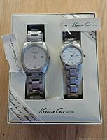 Front view of both watches in box with tags