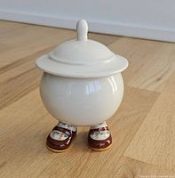 Front view of sugar bowl showing lid, spherical body, shoes and socks