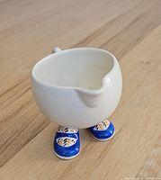 Front view of ceramic creamer standing on blue shoes