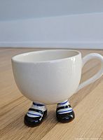 Full view of ceramic mug showing leg base, socks and shoes