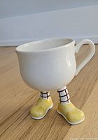 Front view of ceramic mug with yellow boots and checked socks