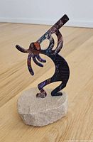 Front view of enamel Kokopelli figure on sandstone base