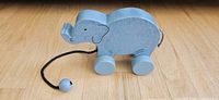 Left side view of blue wooden pull-along elephant toy on wheels with pull cord