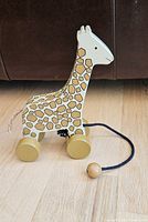left side view of wooden giraffe pull toy showing paint pattern, wheels and pull cord