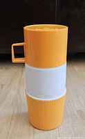 Thermos flask standing upright showing orange lid, white band and orange base