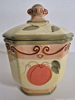 Front view of ceramic canister with lid showing fruit design and swirl accents