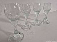 Four clear crystal cordial glasses lined up