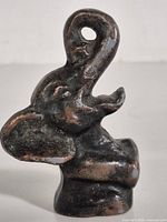 Front view of cast iron elephant bottle opener showing trunk loop and surface wear