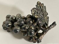 Full view of metal grape cluster with leaf and stem