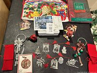 Overall lot layout showing tablecloth package, tote, coasters, pewter ornaments, bell hangers