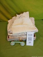 Stack of vintage baby garments in box with ceramic telephone rattle