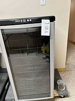 Front view of silver and black wine fridge with glass door and control panel