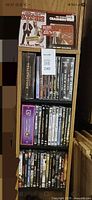 Front view showing wooden shelf and all DVDs, three sealed on top tier