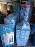 Stacks of Rubbermaid totes wrapped in plastic bags and boxed Hirsch 8-shelf shelving unit